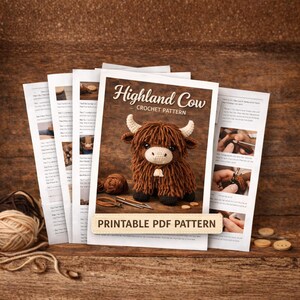 A stack of printed pages with a crochet pattern for a Highland Cow. The cover features a brown crochet cow with white horns and a cream-colored face. The text "Highland Cow Crochet Pattern" is displayed above the cow. The words "Printable PDF Pattern" are at the bottom.