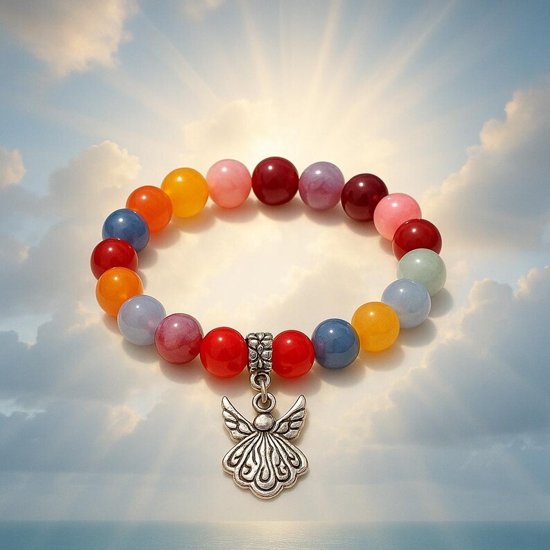 Pode incluir: Uma pulseira de contas com contas redondas coloridas em tons de vermelho, laranja, amarelo, rosa, azul e roxo. A pulseira apresenta um berloque de anjo prateado. O fundo &eacute; um c&eacute;u com nuvens e luz solar.