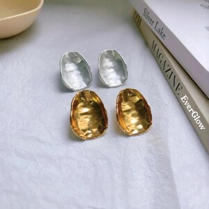Peut inclure: Une paire de boucles d'oreilles avec une finition en m&eacute;tal martel&eacute;. Une paire est dor&eacute;e et l'autre est argent&eacute;e.