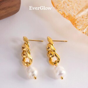 May include: Gold-toned chain earrings with a dangling white pearl and a small gold bead. The earrings have a post back. The word "EverGlow" is in the upper left corner.