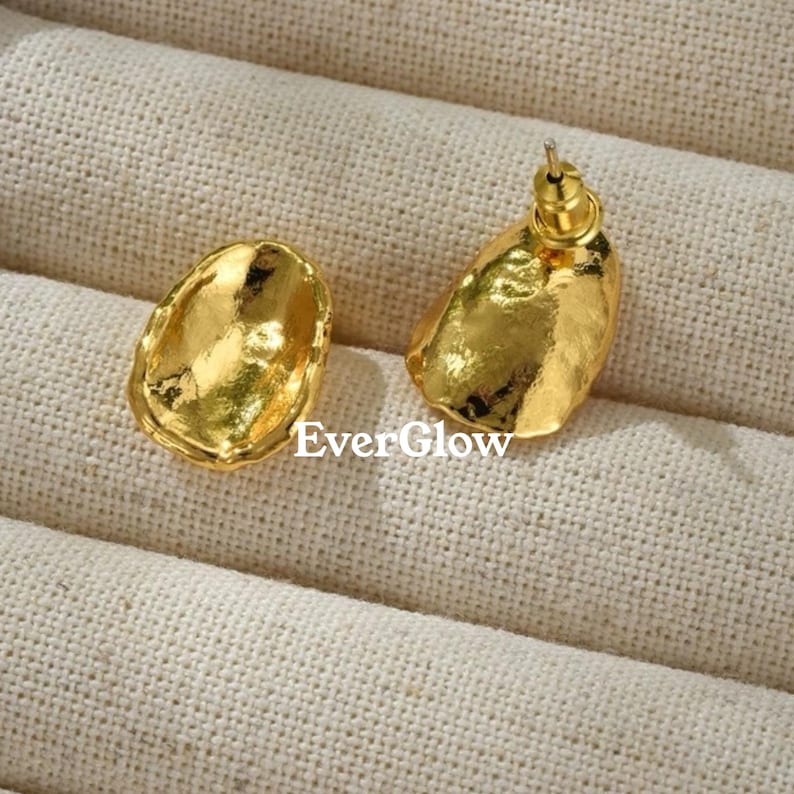 Peut inclure: Une paire de boucles d'oreilles dor&eacute;es avec une forme ovale irr&eacute;guli&egrave;re textur&eacute;e. Les boucles d'oreilles ont une tige et un fermoir papillon.