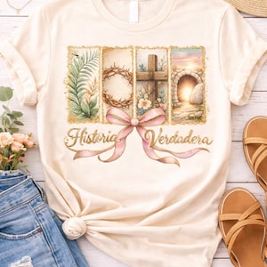 Op de afbeelding: Crèmekleurig T-shirt met een grafische afbeelding met vier ingelijste afbeeldingen: bladeren, een doornenkroon, een kruis en een open graf. Een roze strik en de woorden "Historia Verdadera" staan eronder. Het shirt wordt gecombineerd met een spijkerbroek en sandalen.