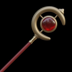 May include: A gold wand with a red gemstone set in a crescent moon-shaped top. The wand has a red wooden shaft.
