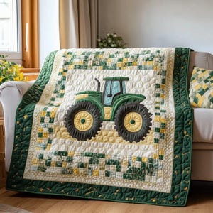 May include: A quilted blanket featuring a green tractor design. The tractor has large black tires with yellow centers and is set against a white background. The blanket has a green and yellow border and is draped over a sofa.