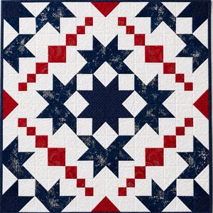 May include: A square quilt with a star pattern in navy blue, red, and white. The quilt features large navy blue stars with a floral pattern, red squares and triangles, and white squares. The central star is navy blue with a small dot pattern.