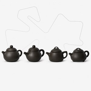 May include: Four small, dark brown, matte-finish teapots arranged in a horizontal row. Each teapot features a rounded body, a short spout, a curved handle, and a removable lid with a knob or loop handle. The teapots have a uniform, earthy texture.