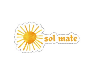 May include: A die-cut sticker featuring a yellow watercolour-style sun with radiating rays on the left side and the text "sol mate" in a bold, orange serif font on the right side, all outlined with a thin white border against a plain background.