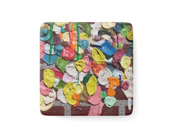 May include: A square coaster featuring a textured, multi-coloured surface covered in numerous small, raised, rounded blobs of paint in shades of yellow, pink, blue, green, orange, and white, layered over a dark red brick-patterned background.