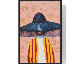 May include: A framed art print featuring a stylized portrait. The subject wears a large, dark blue hat with a red accent and a yellow and red striped coat over a white shirt. The background is a light pink with floral patterns.