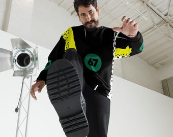 May include: Black long-sleeve sweatshirt with yellow and white accents, and a green circle with the number 67. The person is wearing black pants and black boots with a thick sole. The background is white.