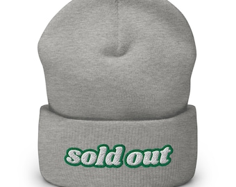 May include: A gray beanie with the words "sold out" embroidered in green on the folded brim. The beanie is made of a soft, knitted material and is suitable for cold weather.