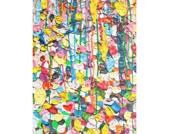 May include: Abstract art piece featuring a colorful arrangement of used chewing gum. The artwork displays a variety of colors, including yellow, pink, blue, and green, with vertical streaks of paint. The gum is arranged in a textured, layered pattern.