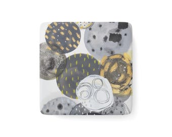 May include: A square ceramic coaster featuring an abstract pattern of overlapping circles in shades of grey, charcoal, and white. The design includes gold-toned brushstroke accents, fine black line drawings, and dotted textures across the surface.