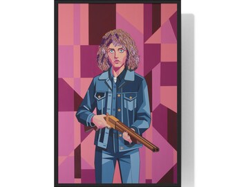 May include: Framed art print featuring a person in a denim jacket and jeans holding a rifle. The artwork has a geometric background in shades of pink and burgundy. The person has curly hair and is looking directly at the viewer.