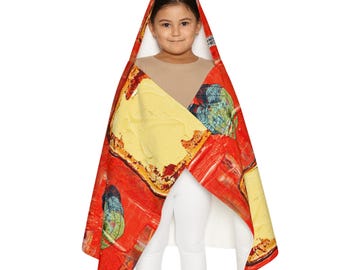 May include: A hooded blanket featuring a vibrant red background with a repeating pattern of yellow butter pats and green leaf illustrations. The hooded design allows for draping over the shoulders, showcasing a bold, colourful food-themed print.