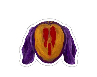 May include: A die-cut sticker featuring an oil painting style illustration of a face with a golden-yellow oval centre, deep purple side panels resembling ears or hair, and three vertical red streaks running down the middle of the face.
