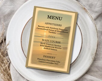 May include: A menu card with a beach scene background sits on a white plate. The menu lists appetizers, main courses, and desserts. The menu items include burrata, chicken, risotto, and chocolate cake. The card has a gold border.