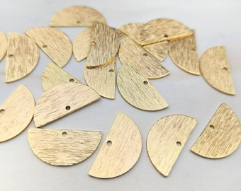May include: A collection of gold-coloured metal half-circle shapes with a hole in the centre. The shapes are arranged in a random pattern on a white surface.