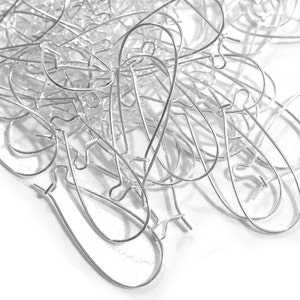 May include: A pile of silver earring hooks, a common jewellery finding used for making earrings.