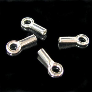 May include: Four silver-toned metal end caps with a small loop on one end and a flat, cylindrical end on the other. These end caps are commonly used in jewellery making.