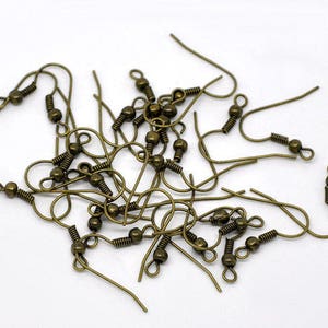 May include: A pile of bronze-colored earring hooks with a small ball at the end of each hook.