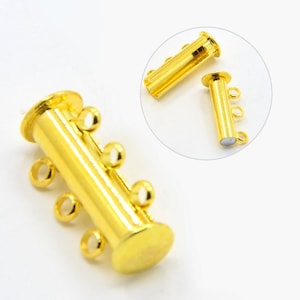 May include: Gold-toned magnetic clasp for jewelry making. The clasp has four loops on each side for attaching chains or cords. The clasp is made of metal and has a shiny finish.