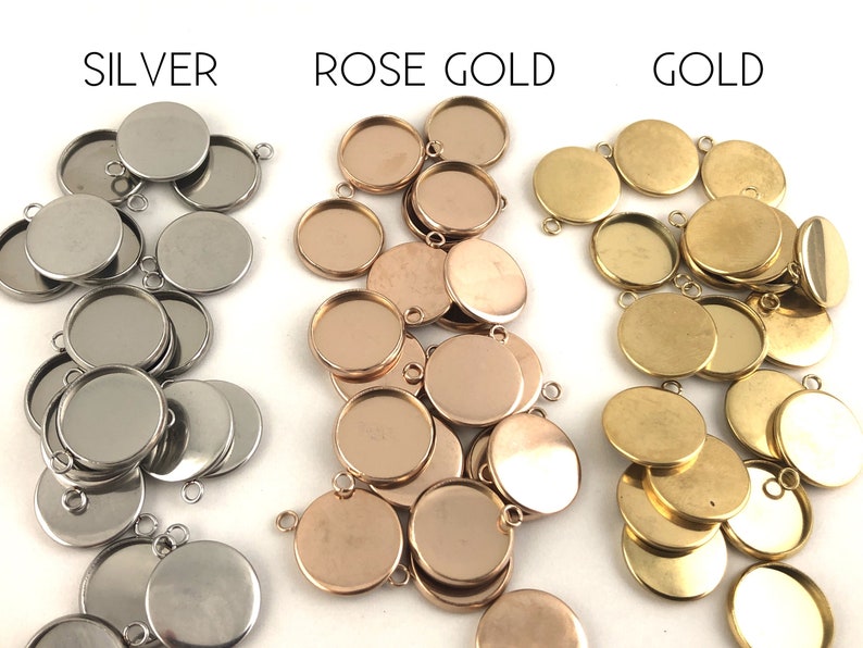 May include: A collection of round metal pendant trays in silver, rose gold, and gold. The trays are designed to hold small items, such as photos, charms, or other decorative elements.