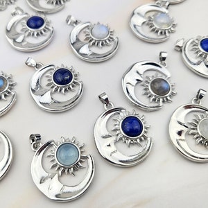 May include: A collection of silver pendants featuring a crescent moon and sun design with various gemstone inlays, including blue, white, and grey.