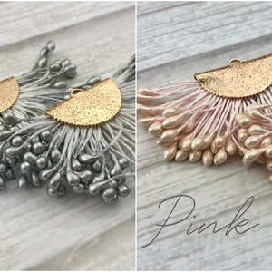 May include: Two pairs of earrings with a gold half-circle design and a fringe of small, teardrop-shaped beads. One pair has gray beads and the other has pink beads.