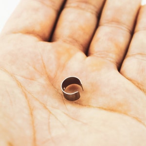May include: A silver metal ring with a rounded shape, lying on a person's palm.