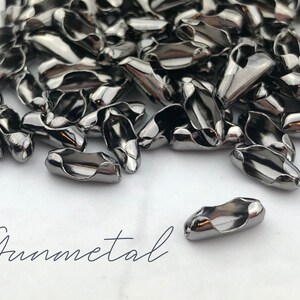 Puede incluir: Un conjunto de cierres de joyer&iacute;a de color plomo. Los cierres tienen forma ovalada con un dise&ntilde;o curvo y un agujero en cada extremo para sujetarlos a la joyer&iacute;a. La palabra "Gunmetal" est&aacute; escrita en cursiva.