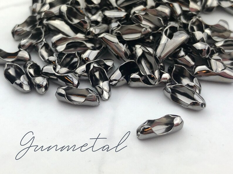 Puede incluir: Un conjunto de cierres de joyer&iacute;a de color plomo. Los cierres tienen forma ovalada con un dise&ntilde;o curvo y un agujero en cada extremo para sujetarlos a la joyer&iacute;a. La palabra "Gunmetal" est&aacute; escrita en cursiva.