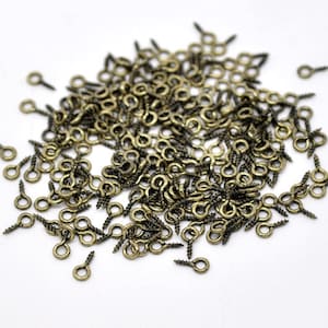 May include: A large quantity of small, antique gold-toned screw-in eyelet hooks. These are ideal for adding a touch of vintage charm to craft projects.