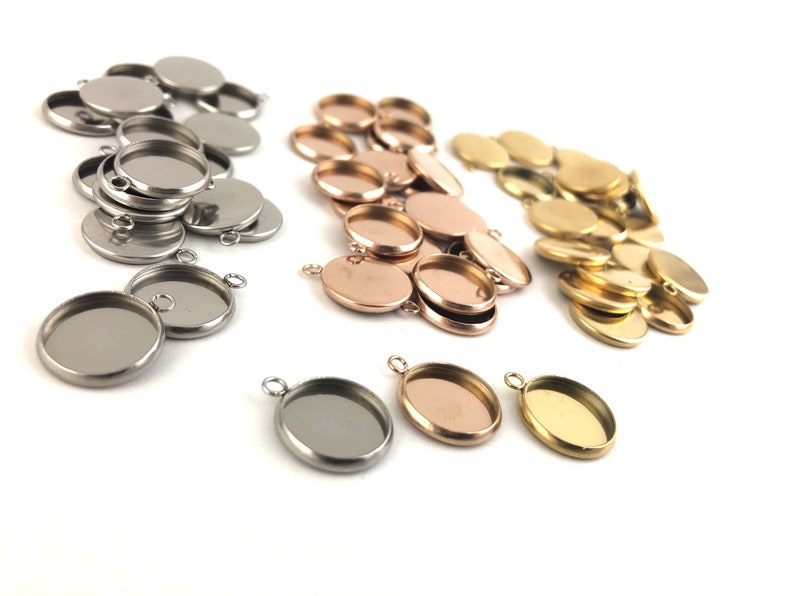 May include: A collection of round metal pendant trays in silver, gold, and rose gold. The trays have a smooth, shiny finish and are ideal for adding a personal touch to jewellery projects.