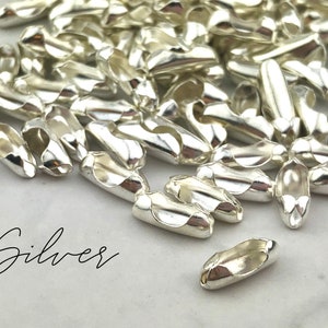 Puede incluir: Un conjunto de cierres de joyer&iacute;a plateados brillantes. Los cierres tienen forma ovalada con un dise&ntilde;o curvo y una peque&ntilde;a abertura en cada extremo. La palabra "Silver" est&aacute; escrita en cursiva en la parte inferior izquierda.