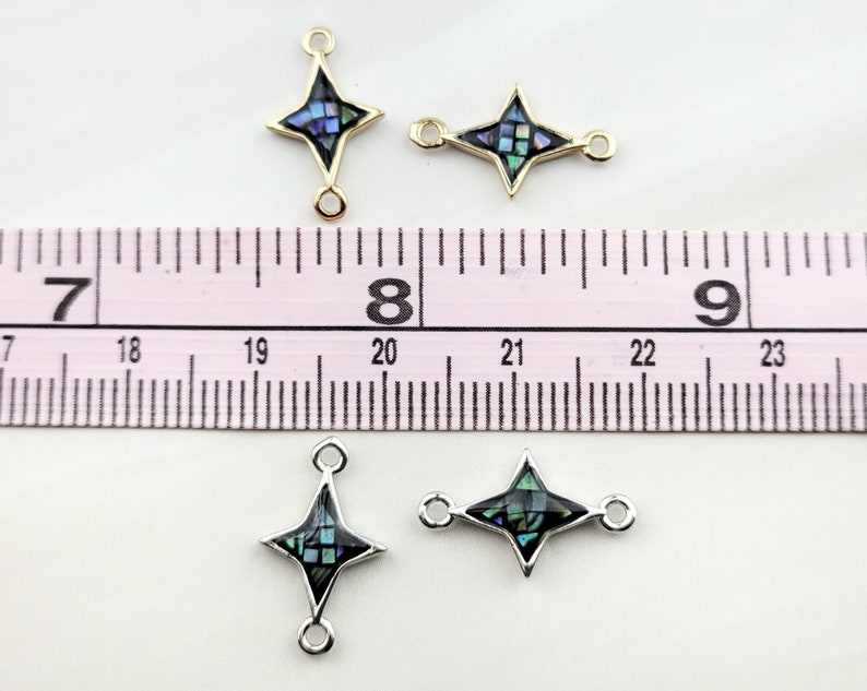 May include: Three gold and silver tone star-shaped connector charms with abalone shell inlay. The charms are approximately 1 inch in length and have two jump rings on each charm.