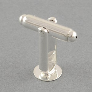 May include: Silver cufflinks with a cylindrical design and rounded ends.