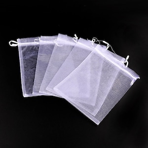 May include: Five white organza gift bags with drawstrings. The bags are made of sheer fabric and are perfect for small gifts or favors.