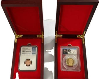 May include: Two dark wood display cases with red velvet interiors, each containing a slabbed coin. The left case holds a copper-toned coin in a white NGC holder. The right case holds a gold-toned Andrew Johnson coin in a clear plastic holder.