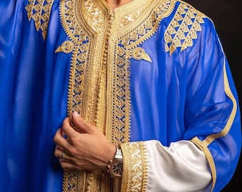 Può includere: Una vivace veste blu con ricami dorati intricati. La veste presenta motivi ornati lungo il colletto, i polsini e la parte anteriore, creando un aspetto lussuoso. Le maniche sono lunghe e i polsini sono bianchi con finiture dorate. Lo sfondo è nero.