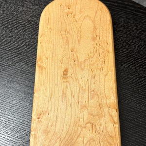 以下が含まれることがあります： ボトル型のデザインの明るい色の木製まな板。ボードは天然の木目模様で、上部にタグが付いています。タグには数字の40が書かれています。