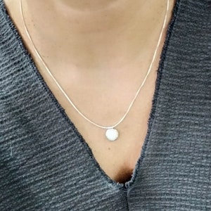May include: A silver chain necklace with a small, round pendant.