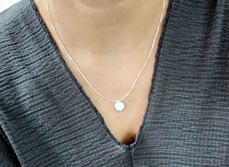 May include: A silver chain necklace with a small, round pendant.