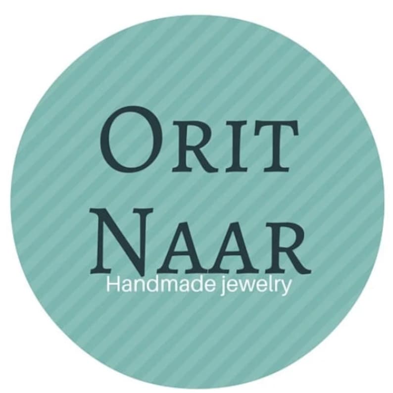 May include: A teal circle with a white striped pattern and the text "ORIT NAAR Handmade jewelry" in black.