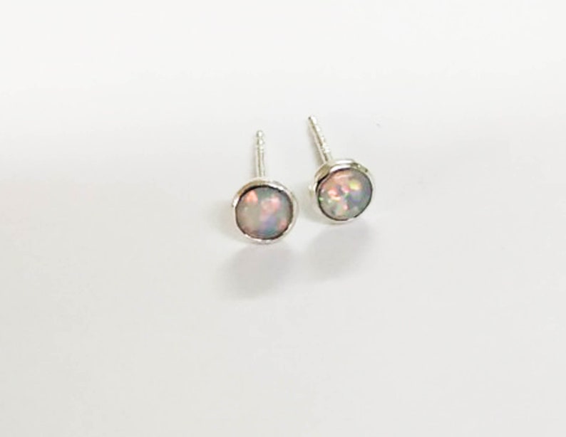 May include: A pair of silver stud earrings with iridescent opal stones.