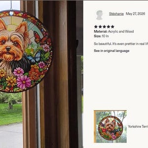 May include: A circular suncatcher featuring a Yorkshire Terrier surrounded by colorful flowers and butterflies. The design is printed on acrylic and wood, measuring 10 inches in diameter. The artwork displays a vibrant stained glass style.