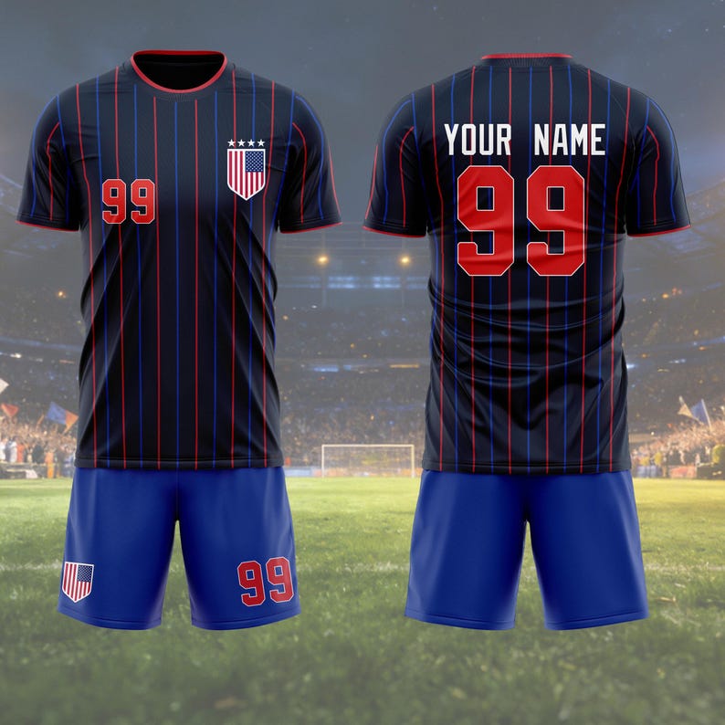 May include: A navy blue soccer jersey and shorts set. The jersey features red and blue vertical stripes, the number 99, and a US flag emblem. The shorts are blue with the number 99. The back of the jersey has the text "YOUR NAME" and the number 99.