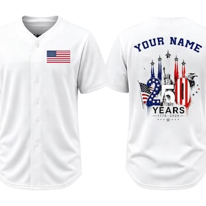 May include: A white button-down baseball jersey featuring a small American flag on the front. The back displays a graphic with the text YOUR NAME, 250 YEARS, and 1776-2026, alongside images of fighter jets, the Statue of Liberty, and an eagle.