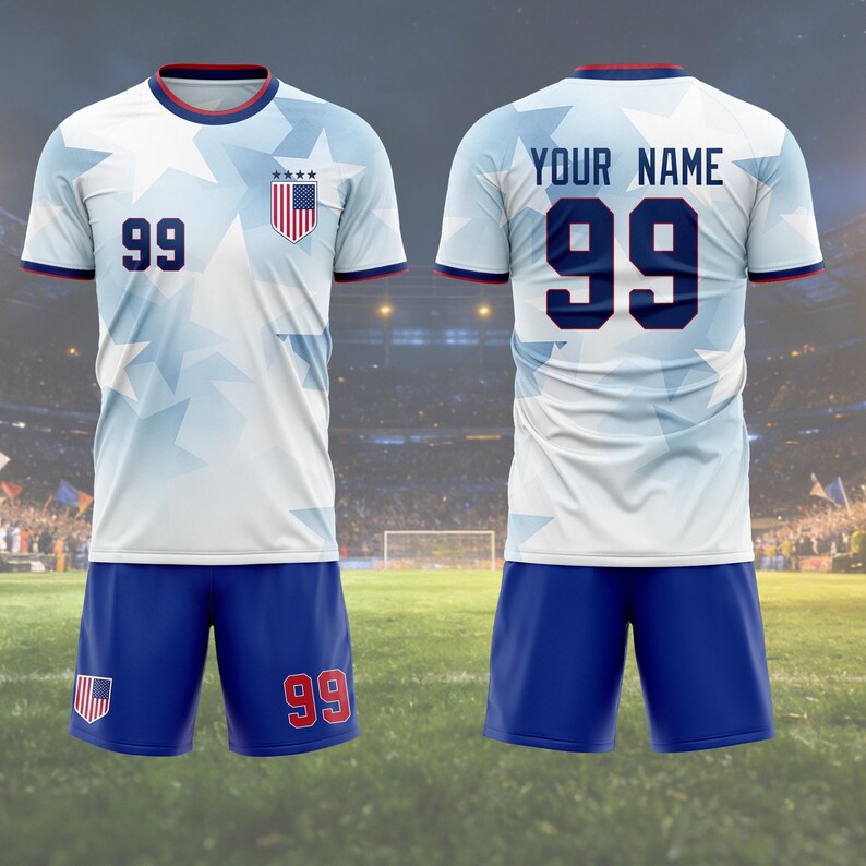 May include: A white and blue soccer uniform with the number 99 on the front and back. The jersey has a star pattern and a US flag crest. The shorts are blue with the number 99 on the right leg. The text "YOUR NAME" is above the number on the back.