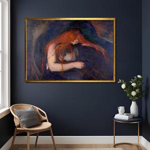 Könnte beinhalten: Ein gerahmtes Gemälde mit goldenem Rahmen zeigt eine Frau mit langen roten Haaren, die sich vorbeugt und ein dunkles Objekt hält. Das Kunstwerk ist vor einem dunkelblauen Hintergrund platziert, was einen dramatischen Kontrast erzeugt. Das Gemälde ist ein Kunstwerk.